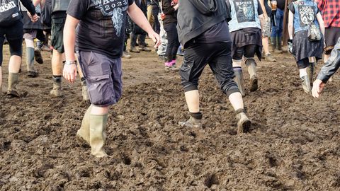 Fans laufen auf dem Wacken-Festival mit Gummistiefel durch den Schlamm