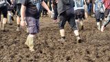 Fans laufen auf dem Wacken-Festival mit Gummistiefel durch den Schlamm
