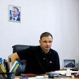 Stremousov an einem Schreibtisch und an der Wand ein Bild von Putin