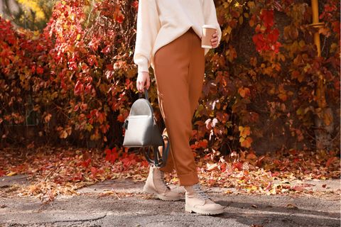 Ein Mensch mit Boots geht über Laub und zeigt die Herbstschuhe Trends