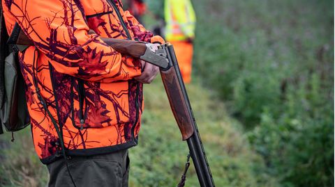Ein Jäger mit Gewehr in der Hand wartet auf den Beginn einer Treibjagd