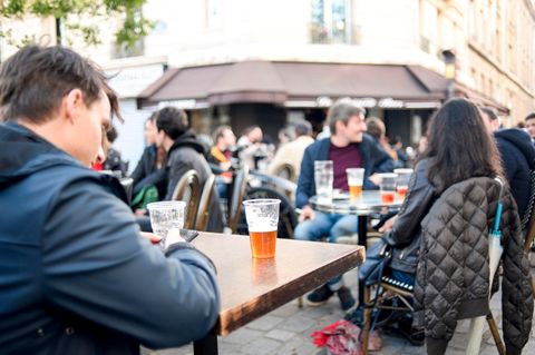 Vor einem Pariser Café sitzen Menschen mit Bier