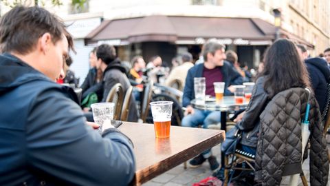Vor einem Pariser Café sitzen Menschen mit Bier