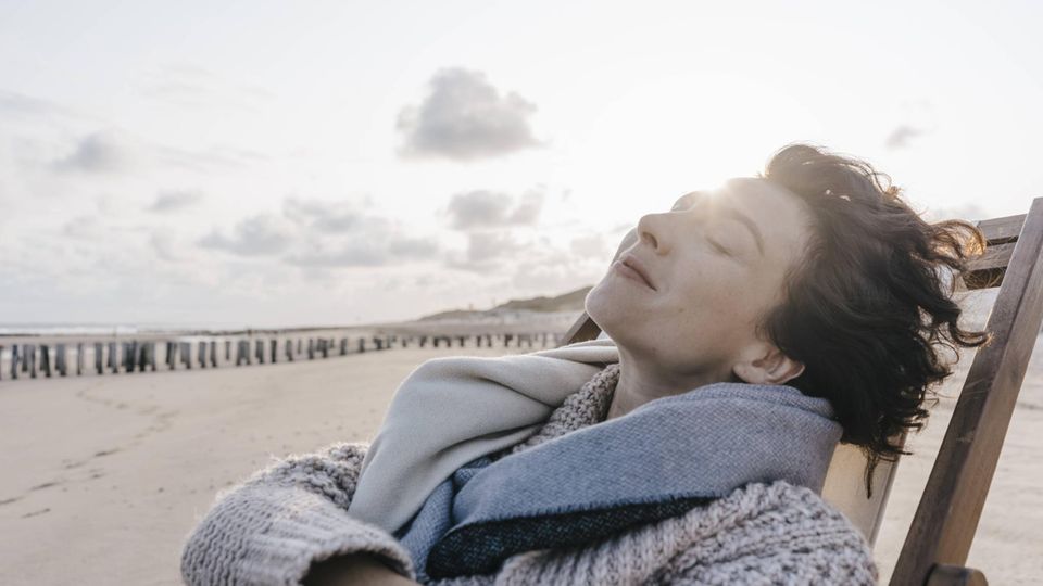 Urlaub: Eine Frau liegt mit geschlossenen Augen auf einem Liegestuhl