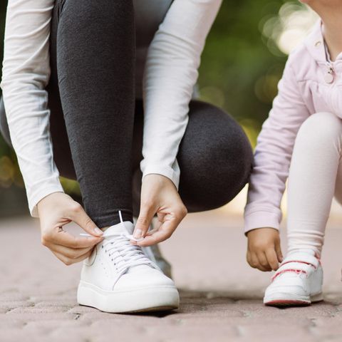 Eine Frau und ihre Tochter binden sich die Schuhe zu