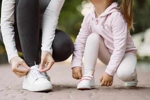 Eine Frau und ihre Tochter binden sich die Schuhe zu