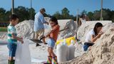 Kinder füllen am Dienstag in der Stadt Pinellas Park an der Westküste Floridas Sandsäcke