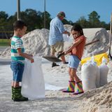 Kinder füllen am Dienstag in der Stadt Pinellas Park an der Westküste Floridas Sandsäcke