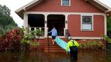 Einwohner in Tarpon Springs tragen ein Boot von der überschwemmten Straße auf ihre Veranda