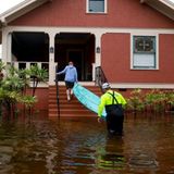 Einwohner in Tarpon Springs tragen ein Boot von der überschwemmten Straße auf ihre Veranda