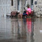 Ein Mann sitzt auf einer Bank auf einer überschwemmten Straße