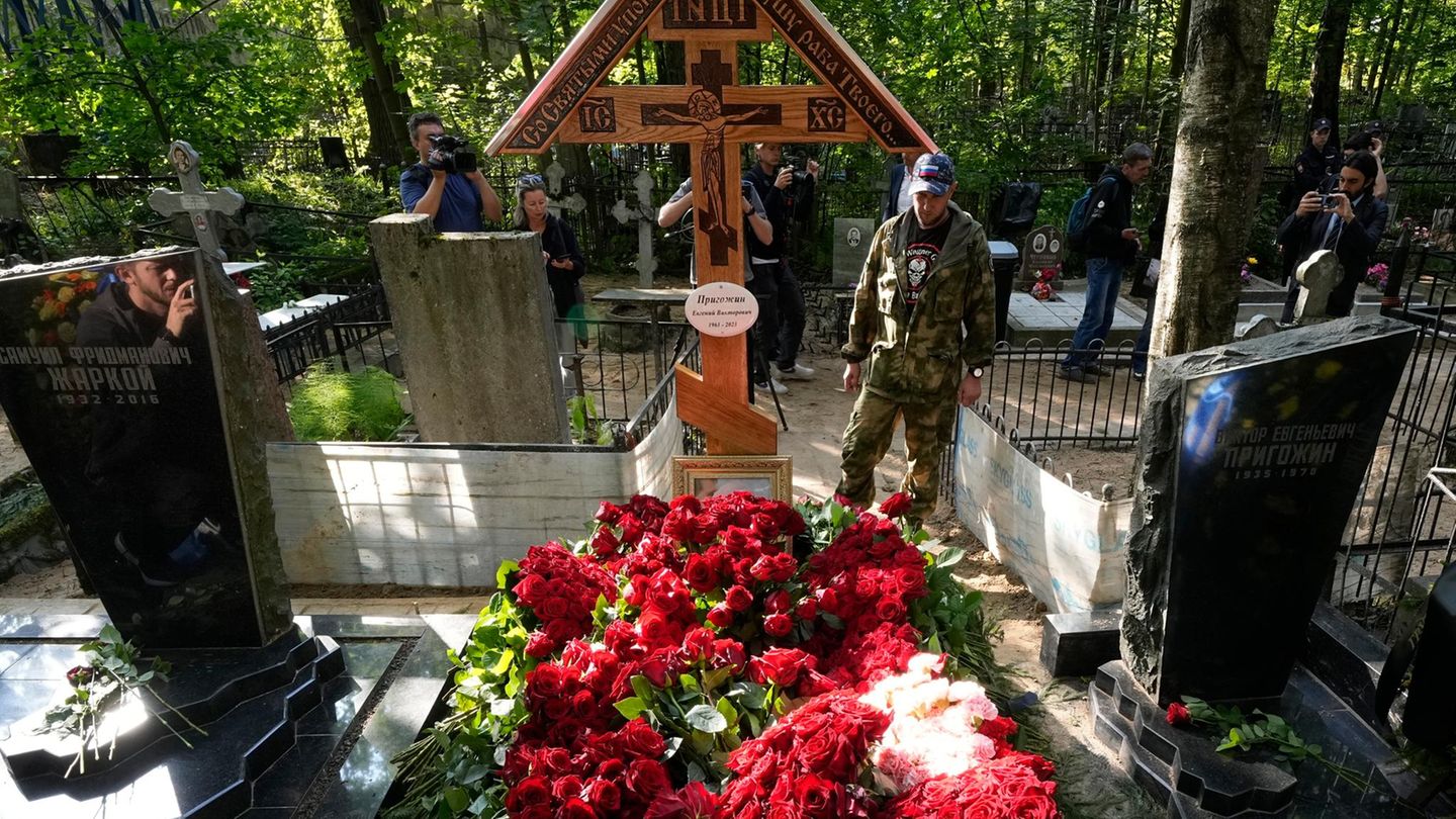 Ein Mann in Militäruniform steht auf dem Friedhof Porochowskoje an einem blumengeschmückten Grab von Jewgeni Prigoschin