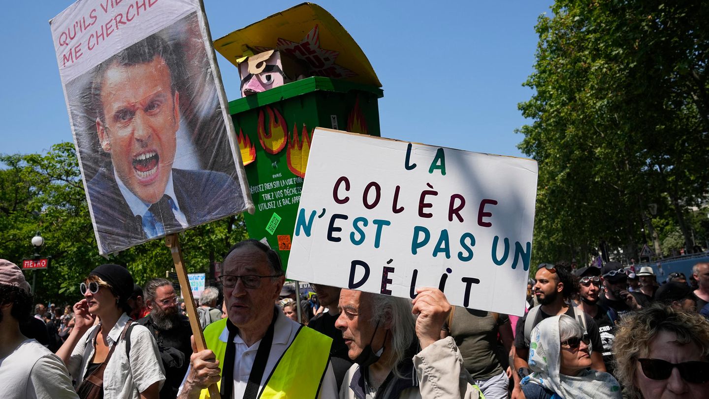 Ein Demonstrant trägt eine Mülltonne mit einem Bildnis, das den französischen Präsidenten Macron darstellt