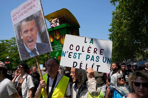Ein Demonstrant trägt eine Mülltonne mit einem Bildnis, das den französischen Präsidenten Macron darstellt