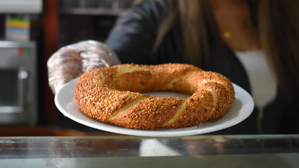 Bäckereiverkäuferin hält einen Teller mit Simit