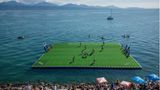Spieler, die auf einem schwimmenden Rugbyfeld auf dem Genfer See um den Ball kämpfen
