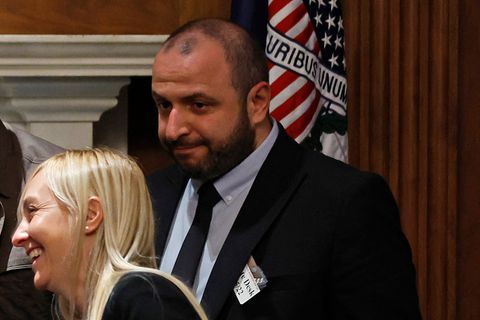 Rustem Umerow steht bei einem Empfang vor einer Flagge mit dem US-Motto "De pluribus unum"
