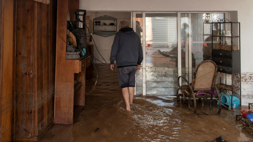 Mann steht in einem überfluteten Wohnzimmer