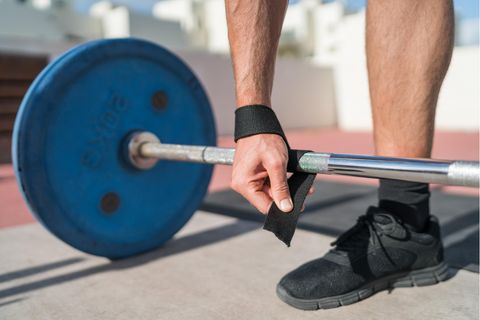 Zughilfen im Krafttraining: Mann fixiert Zughilfen an einer Hantelstange