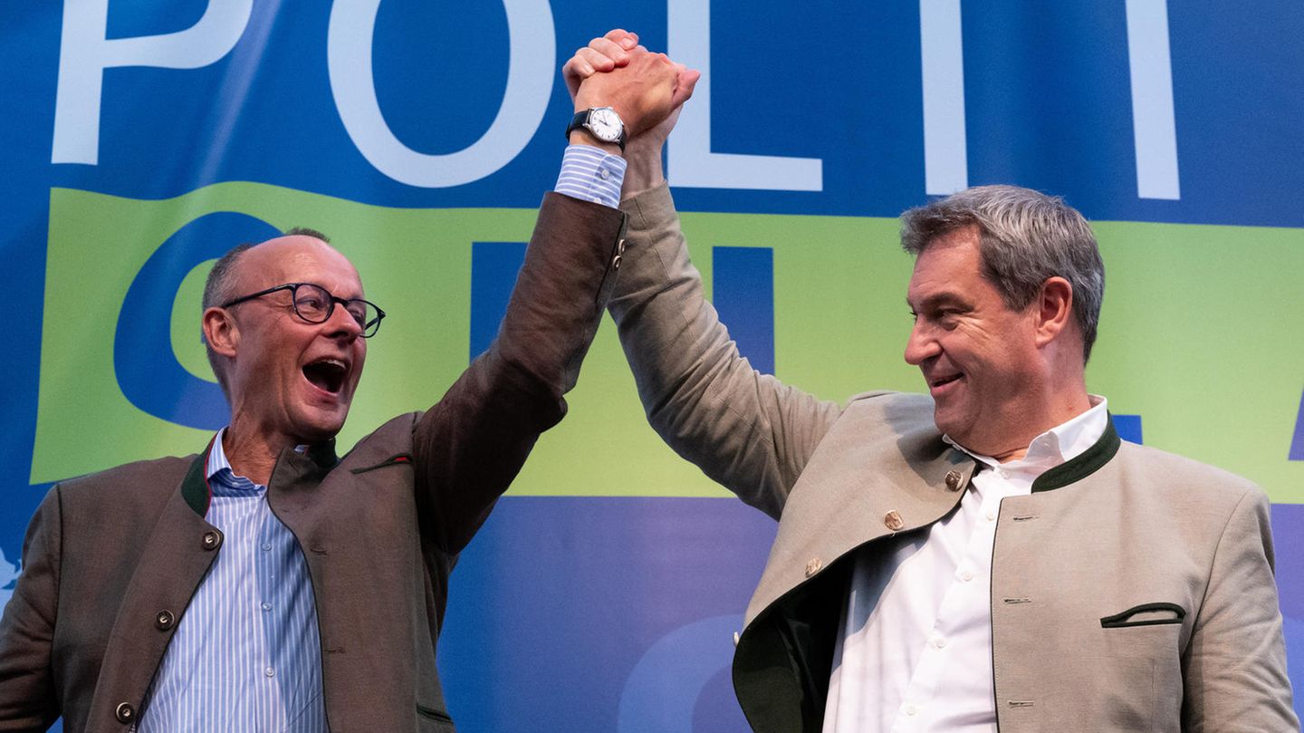 Friedrich Merz und Markus Söder recken beim Gillamoos gemeinsam die Arme in die Höhe