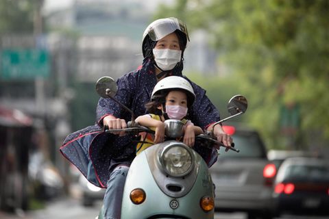Taiwan: Eine Frau sitzt mit ihrem Kind auf einem Roller und fährt durch die Hauptstadt Taipeh