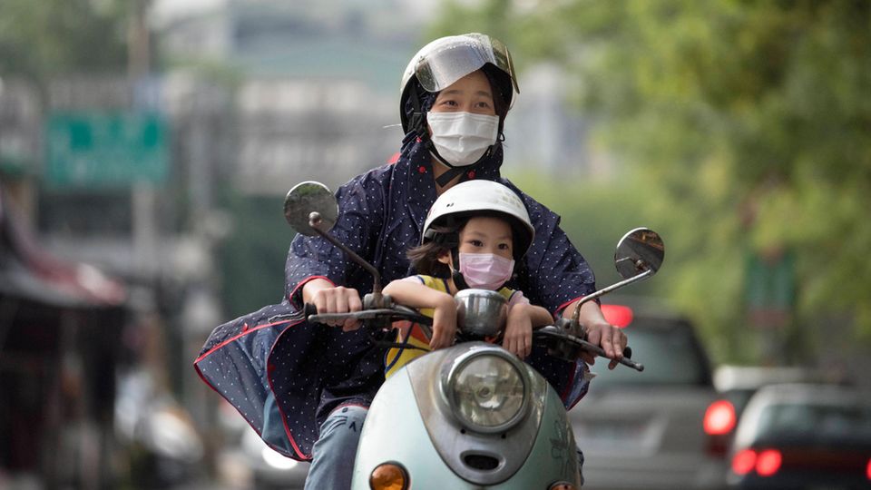 Taiwan: Eine Frau sitzt mit ihrem Kind auf einem Roller und fährt durch die Hauptstadt Taipeh
