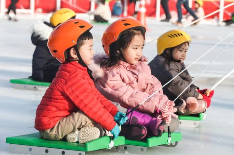 Kinder in Busan, Südkorea, werden auf Schlitten über eine Eisbahn gezogen