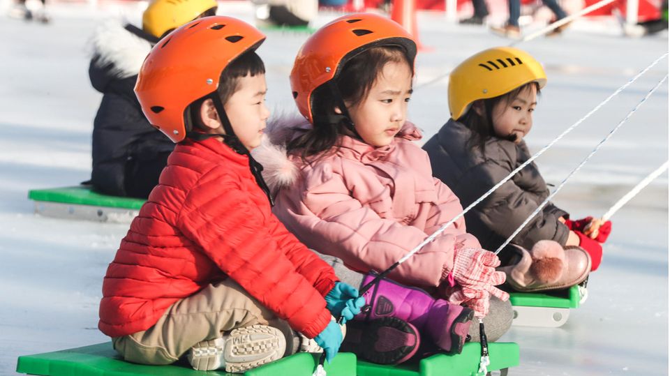 Kinder in Busan, Südkorea, werden auf Schlitten über eine Eisbahn gezogen