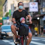 In Taiwan fährt ein Vater mit seinem Kind auf dem Roller