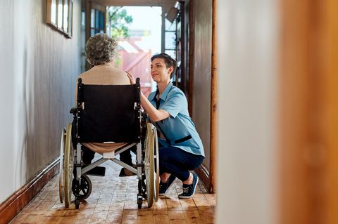 Pflege: Eine Pflegekraft kümmert sich um eine ältere Frau in einem Rollstuhl