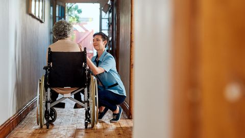 Pflege: Eine Pflegekraft kümmert sich um eine ältere Frau in einem Rollstuhl