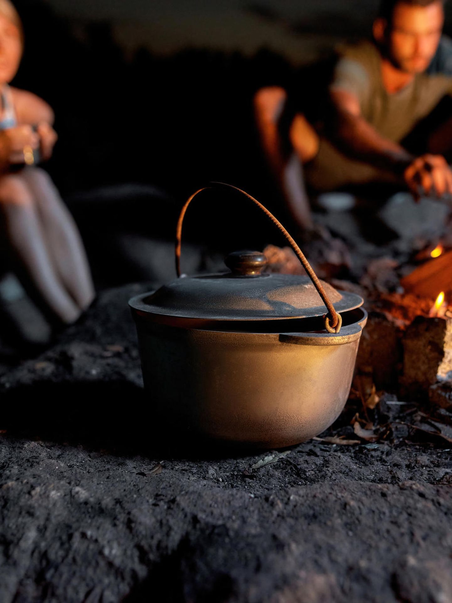 Eine Frau lässt einen Mann Essen probieren, im Vordergrund steht ein Dutch Oven.