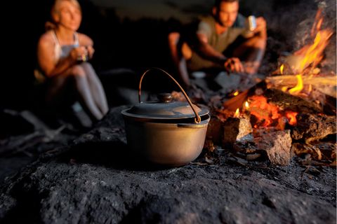 Eine Frau lässt einen Mann Essen probieren, im Vordergrund steht ein Dutch Oven.