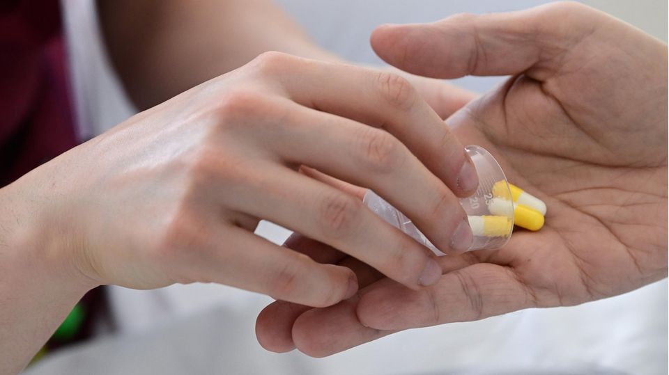 Medikamente für Ältere: Eine Pflegerin gibt in einem Krankenhaus einem Patienten Tabletten