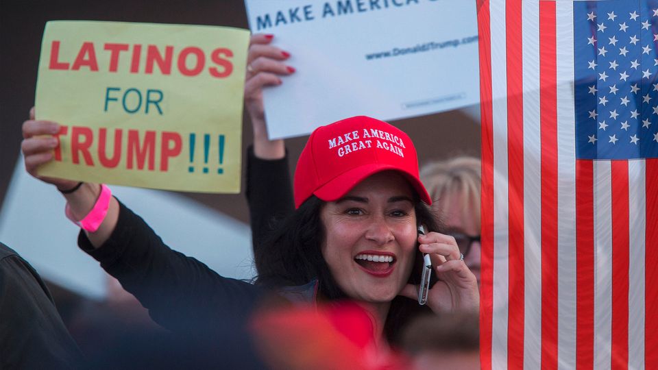 Ein Frau trägt eine Kappe auf der steht "Make America Great Again". Sie hält ein Schild, auf dem Steht: "Latinos for Trump"