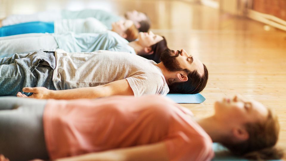 Yoga-Kursteilnehmer liegen bei der Endentspannung auf dem Boden
