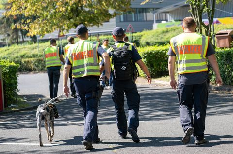 Mit einem Spürhund durchsuchen Polizeibeamte das Gebiet am Schulzentrum in Lohr am Main