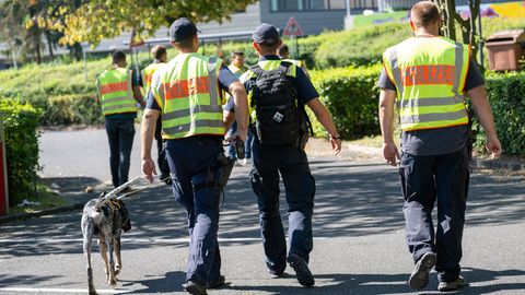 Mit einem Spürhund durchsuchen Polizeibeamte das Gebiet am Schulzentrum in Lohr am Main