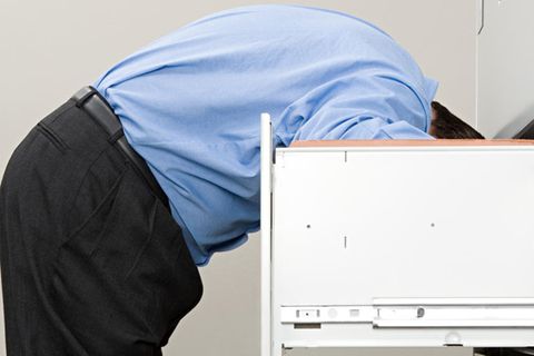 Mann sucht kopfüber etwas in einem Schrank (Symbolbild)