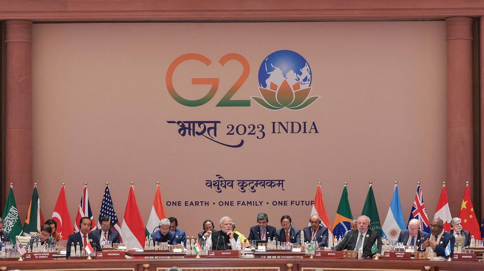 Die Mächtigen der Welt sitzen beim G20 Gipfel in Indien auf einem Podium nebeneinander