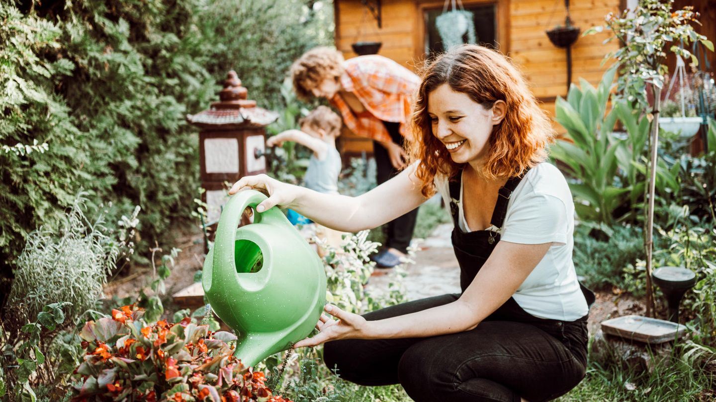 Eine Frau gießt Blumen im Garten.