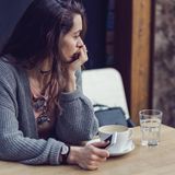 Eine junge Frau blickt zur Seite und grübelt