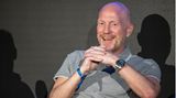 Matthias Sammer sitzt und lacht bei einer Pressekonferenz