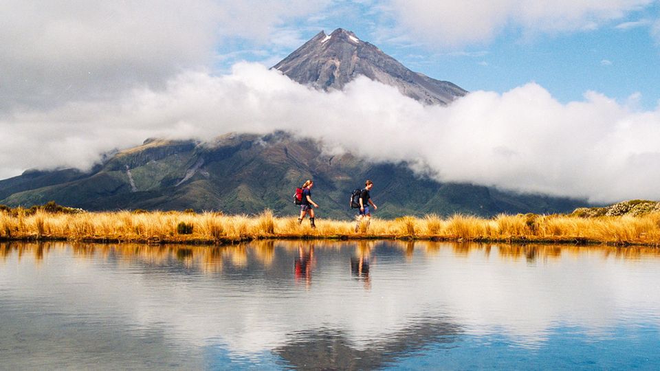 Zwei Wanderer vor dem Mount Taranaki in Neuseeland