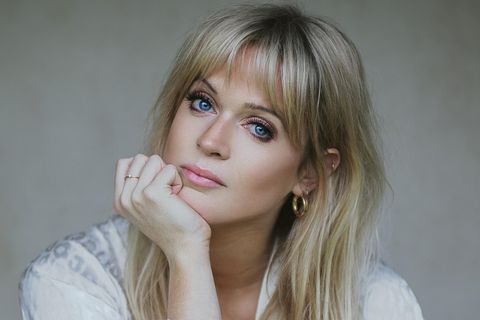 Dolly Alderton, eine junge Frau mit großen Augen und langen Haaren, stützt den Kopf auf ihrer Hand ab