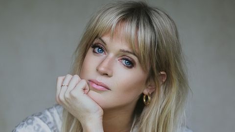 Dolly Alderton, eine junge Frau mit großen Augen und langen Haaren, stützt den Kopf auf ihrer Hand ab