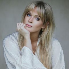 Dolly Alderton, eine junge Frau mit großen Augen und langen Haaren, stützt den Kopf auf ihrer Hand ab