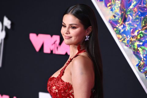 Selena Gomez lächelt in rotem Kleid in die Kamera auf dem roten Teppich