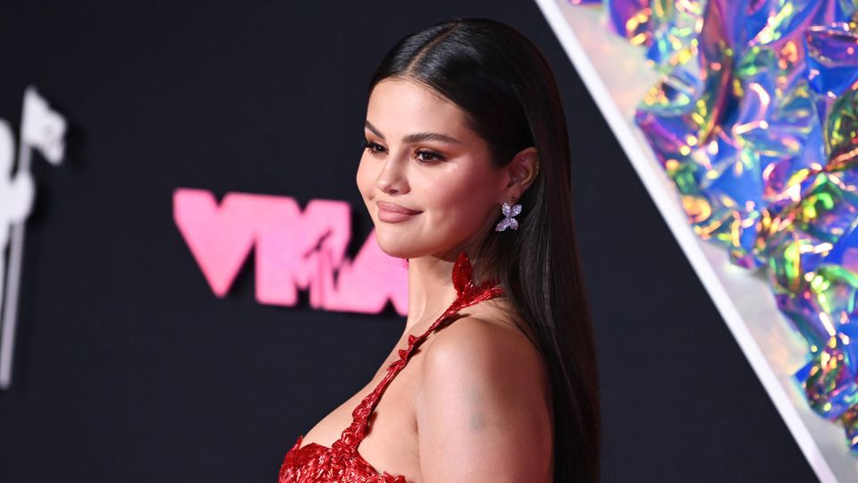 Selena Gomez lächelt in rotem Kleid in die Kamera auf dem roten Teppich