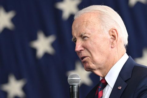 Joe Biden spricht vor einer US-Flagg in ein Mikrofon